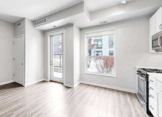 A kitchen with white appliances and a window overlooking a cityscape.