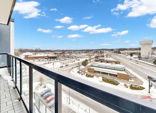 A balcony overlooks a busy highway and a parking lot.