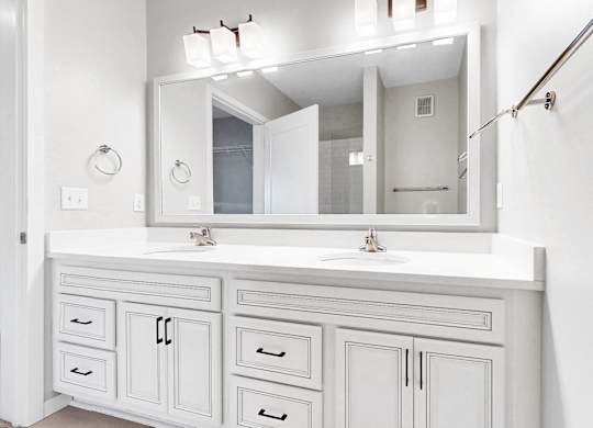 A white bathroom vanity with a mirror and lights above it.