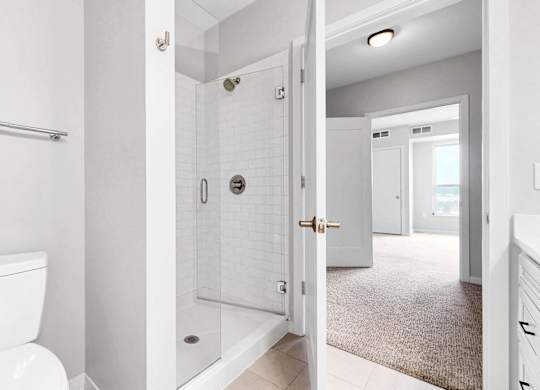A white toilet in a bathroom with a door open to a hallway.
