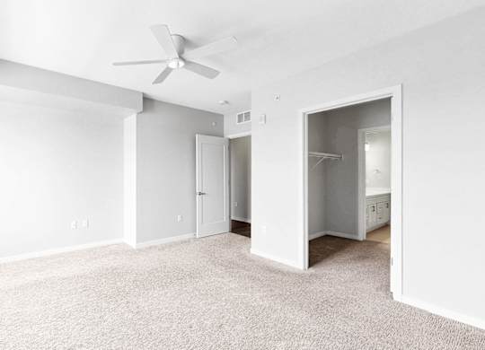 A spacious room with a ceiling fan and carpeted floor.