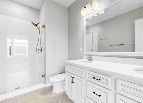 A white bathroom with a toilet, sink, and shower.