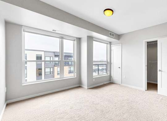 A spacious room with large windows and a carpeted floor.