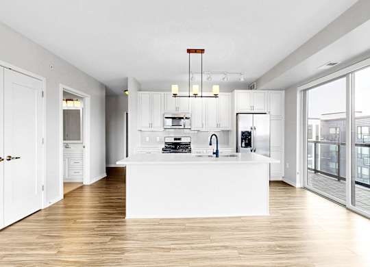 A modern kitchen with white cabinets and a wooden floor.