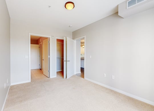 a bedroom with a carpeted floor and a door to a bathroom