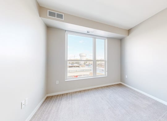 an empty bedroom with large window and white walls