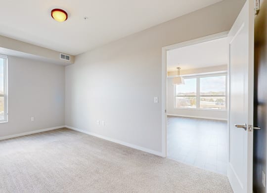 a bright bedroom with two windows and a door