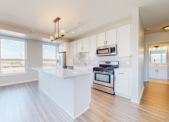 a white kitchen with a large window and a white island