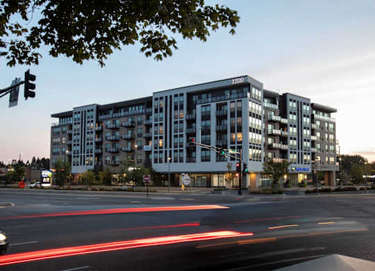 an apartment building at dusk at the intersection of a city street