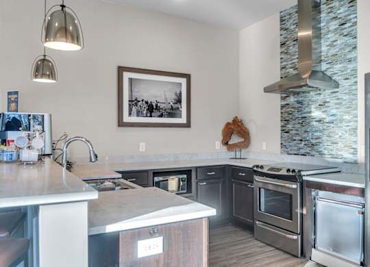 A woman is standing in a kitchen with stainless steel appliances.