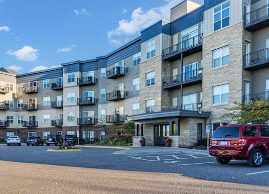 A row of apartment buildings with cars parked in front.