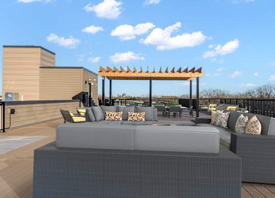 A modern outdoor seating area with grey couches and a wooden pergola.