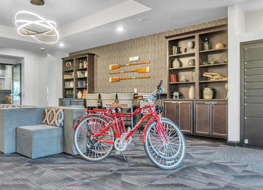 A red bicycle is parked in a room with a grey carpet.