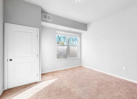 A room with a white door and carpeted floor.