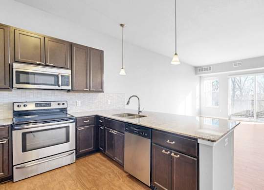 A kitchen with dark brown cabinets and stainless steel appliances.