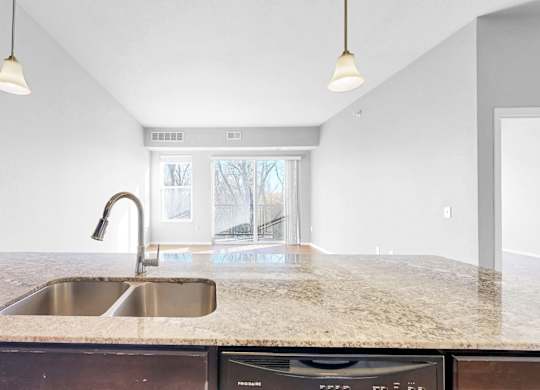 A kitchen with a granite countertop and a stainless steel sink.