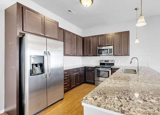 A kitchen with a granite counter top and stainless steel appliances.