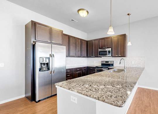 A kitchen with a granite countertop and stainless steel appliances.