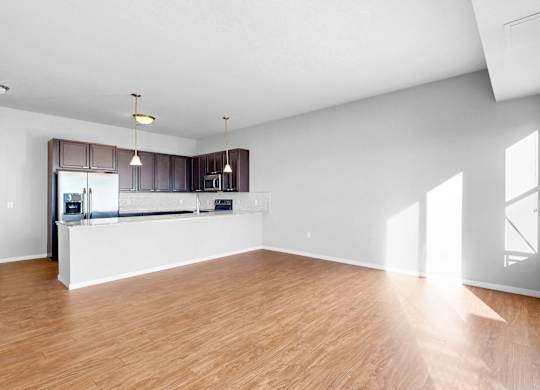 A spacious room with wooden flooring and white walls.