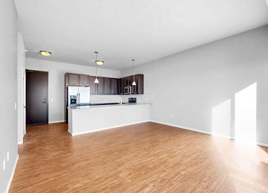 A spacious room with wooden flooring and white walls.