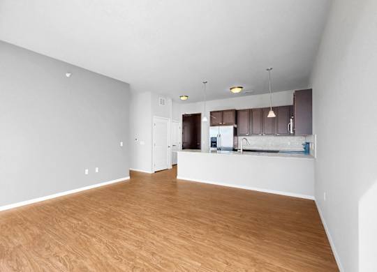 A spacious room with wooden flooring and white walls.