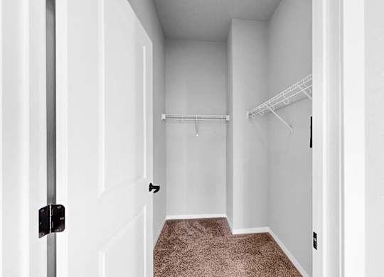 A white door with a black handle is open to a hallway with a carpeted floor.