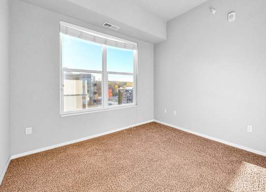 A room with a carpeted floor and a large window.