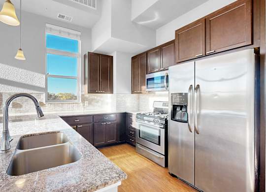 A modern kitchen with a stainless steel refrigerator and a marble countertop.