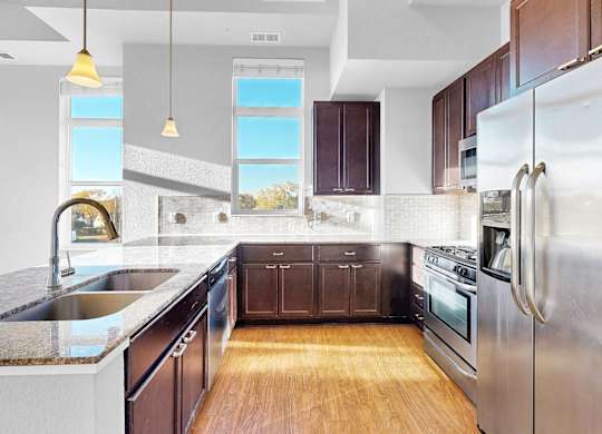 A modern kitchen with dark wood cabinets and stainless steel appliances.