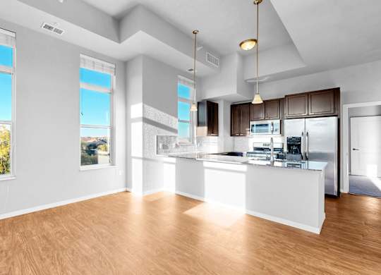 A spacious kitchen with a bar area and a view of trees outside the window.
