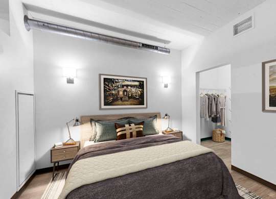 A bedroom with a large bed and two pictures on the wall.