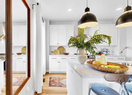 A kitchen with a white color scheme and a large island in the center.at Field and Grove Townhomes of Champlin, Champlin, MN