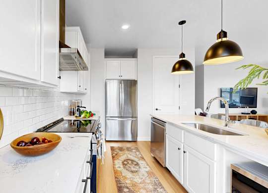 A modern kitchen with white cabinets and a wooden cutting board on the counter.at Field and Grove Townhomes of Champlin, Champlin