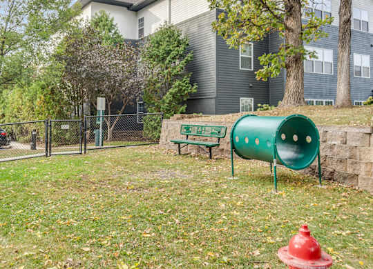 A playground with a green slide and a red fire hydrant.