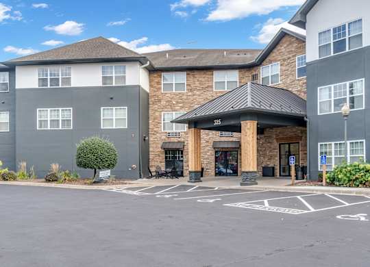 A parking lot in front of a building with a black awning.