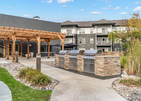 A modern building with a wooden pergola and a stone wall with a sign that reads "Kenmore".
