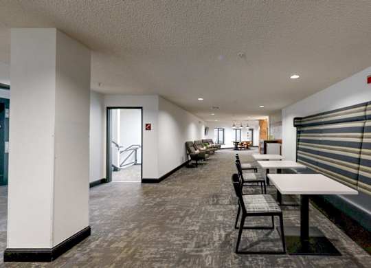 A long white table with chairs is in a room with a bench and a window.