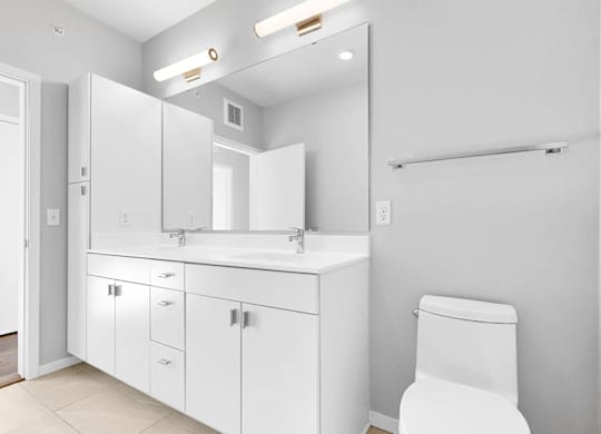 A white bathroom with a toilet, sink, and mirror.