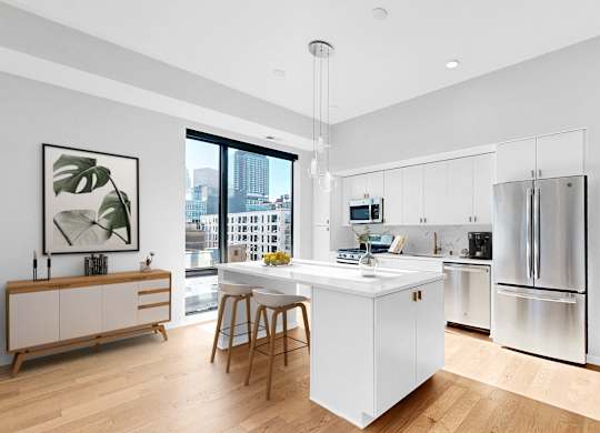 A modern kitchen with a white island and stainless steel appliances.