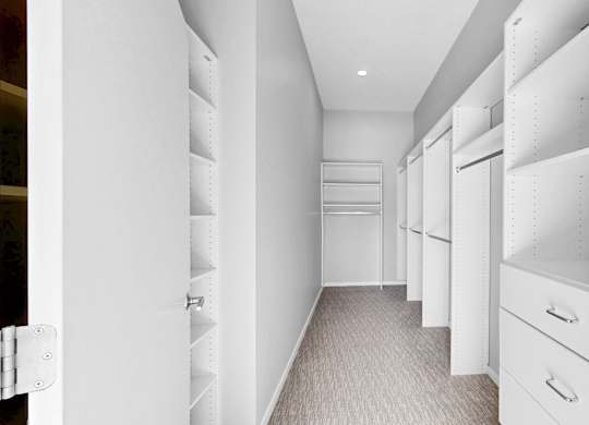 A long hallway with white shelves and drawers.