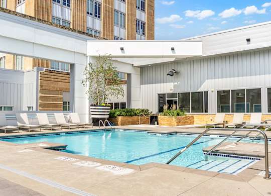 A swimming pool in a courtyard surrounded by chairs and plants.