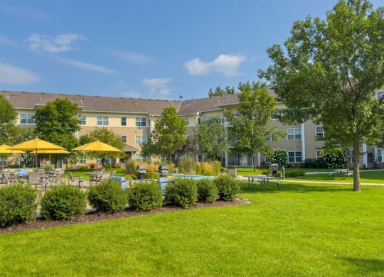 beautiful landscaping with patio with tables chairs and umbrellas