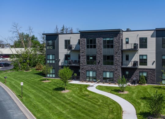 an apartment building with green grass and a sidewalk