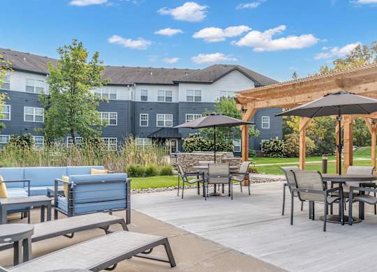 A patio with a table and chairs under a wooden pergola.