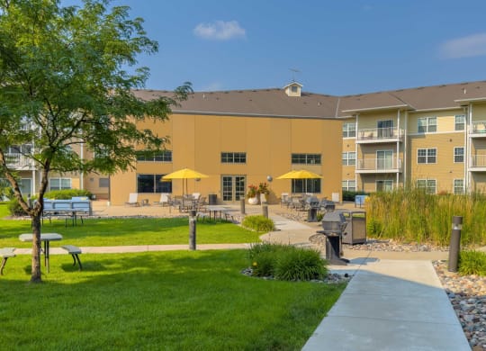 a large apartment building with a lawn and picnic tables