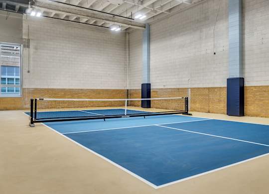 A tennis court with a net and two blue posts.