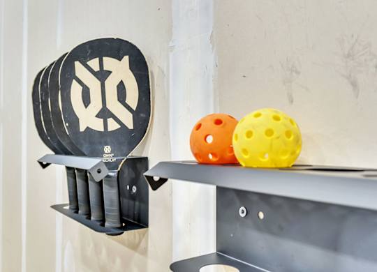 A black and white sign with a symbol on it is hanging on a wall next to a shelf with two colorful balls on it.