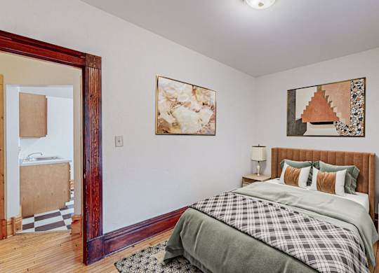 A bedroom with a bed, nightstands, and two pictures on the wall.