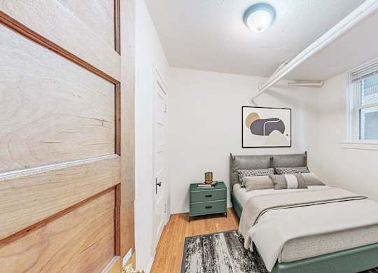 A bedroom with a bed, nightstand, and a painting on the wall.