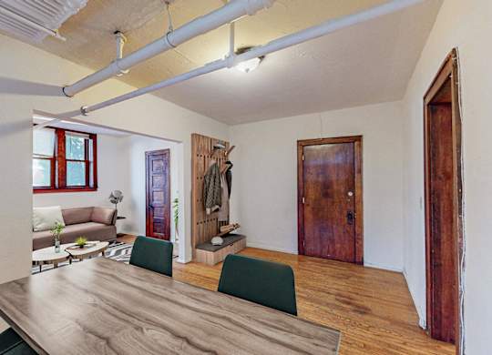 A room with a long wooden table and green chairs.